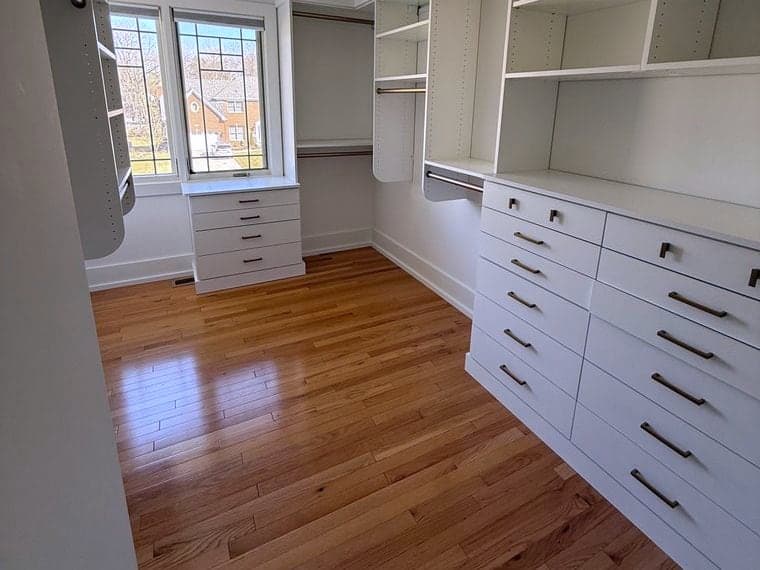 Empty walk-in closet with bare white shelving and a polished hardwood floor after a DSM Cleaning Solutions move-out cleaning
