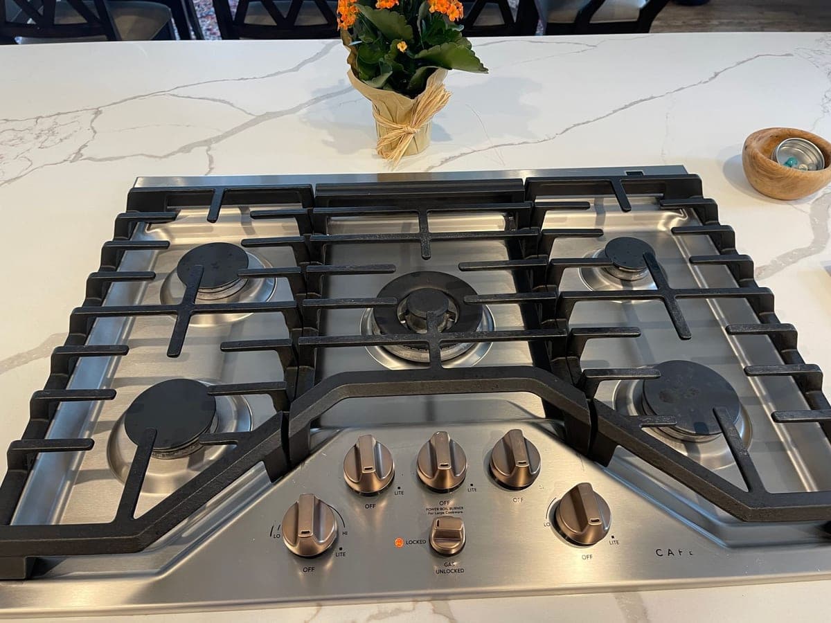 Five-burner gas cooktop with clean grates on a marble countertop after a DSM Cleaning Solutions deep clean