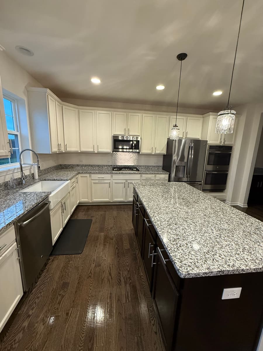 Furnished kitchen with a dark island and hardwood floor after standard house cleaning