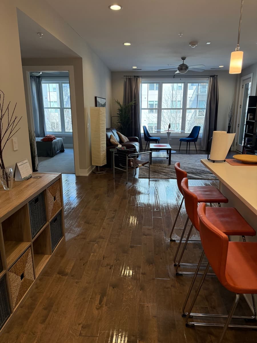 Furnished living and kitchen combo with a glossy hardwood floor catching light after standard house cleaning
