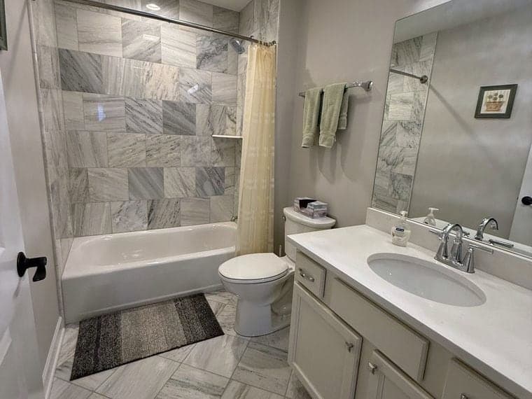 Marble tiled bathroom with a scrubbed tub surround and floor tile catching the light after a DSM Cleaning Solutions deep clean