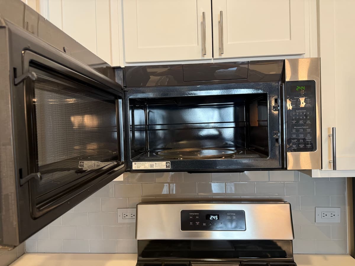 Microwave interior open showing a spotless cavity and clean glass tray after a DSM Cleaning Solutions deep clean