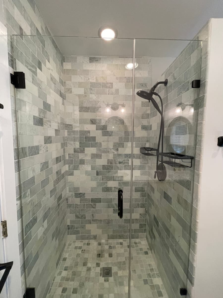 Glass-enclosed shower with mosaic tile and clean grout lines after a DSM Cleaning Solutions deep clean
