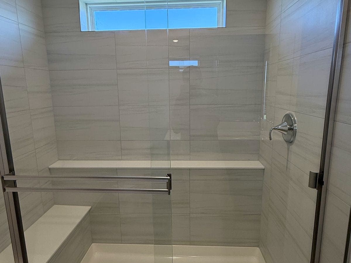 Walk-in shower with streak-free glass doors and a spotless tiled pan after house cleaning by DSM Cleaning Solutions